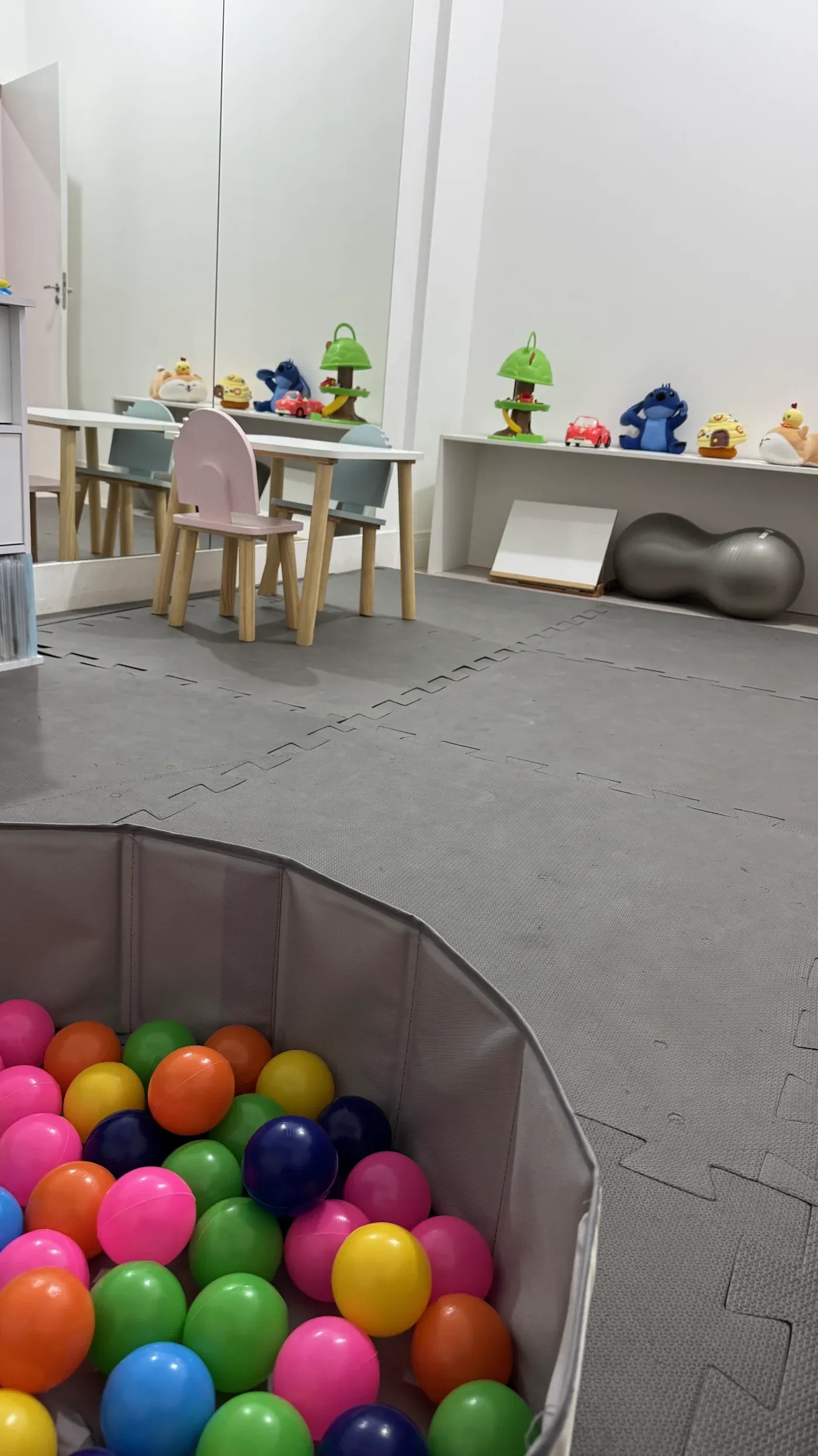 Sala de atendimentos com piscina de bolinhas coloridas, mesa infantil e brinquedos na prateleira